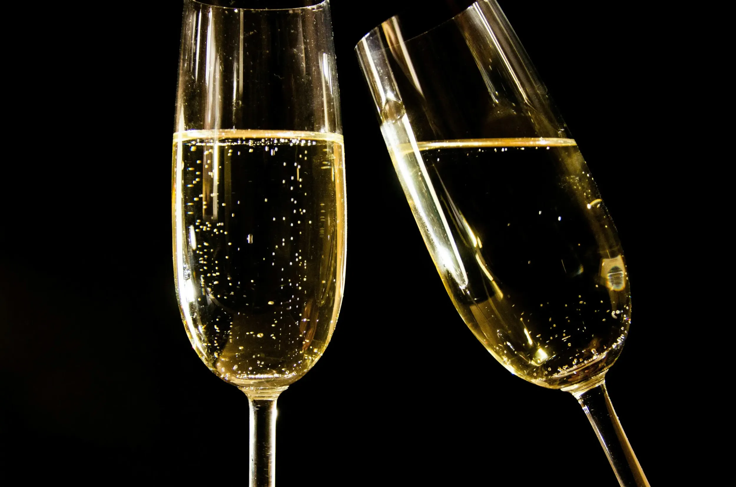Two glasses of sparkling wine against a dark background.