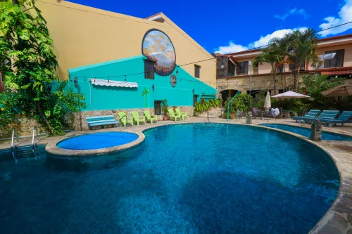 Pool deck with covered hot tub, lime-green lounge chairs, and outdoor dining beyond.