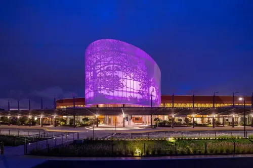 Night exterior showing the purple-lit rotunda and covered arrival walkway.