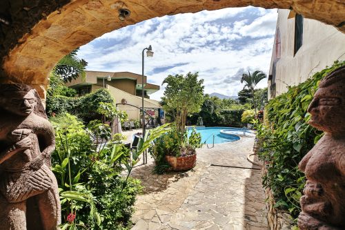 Indigenous stone figures flank the archway and flagstone path to the pool.