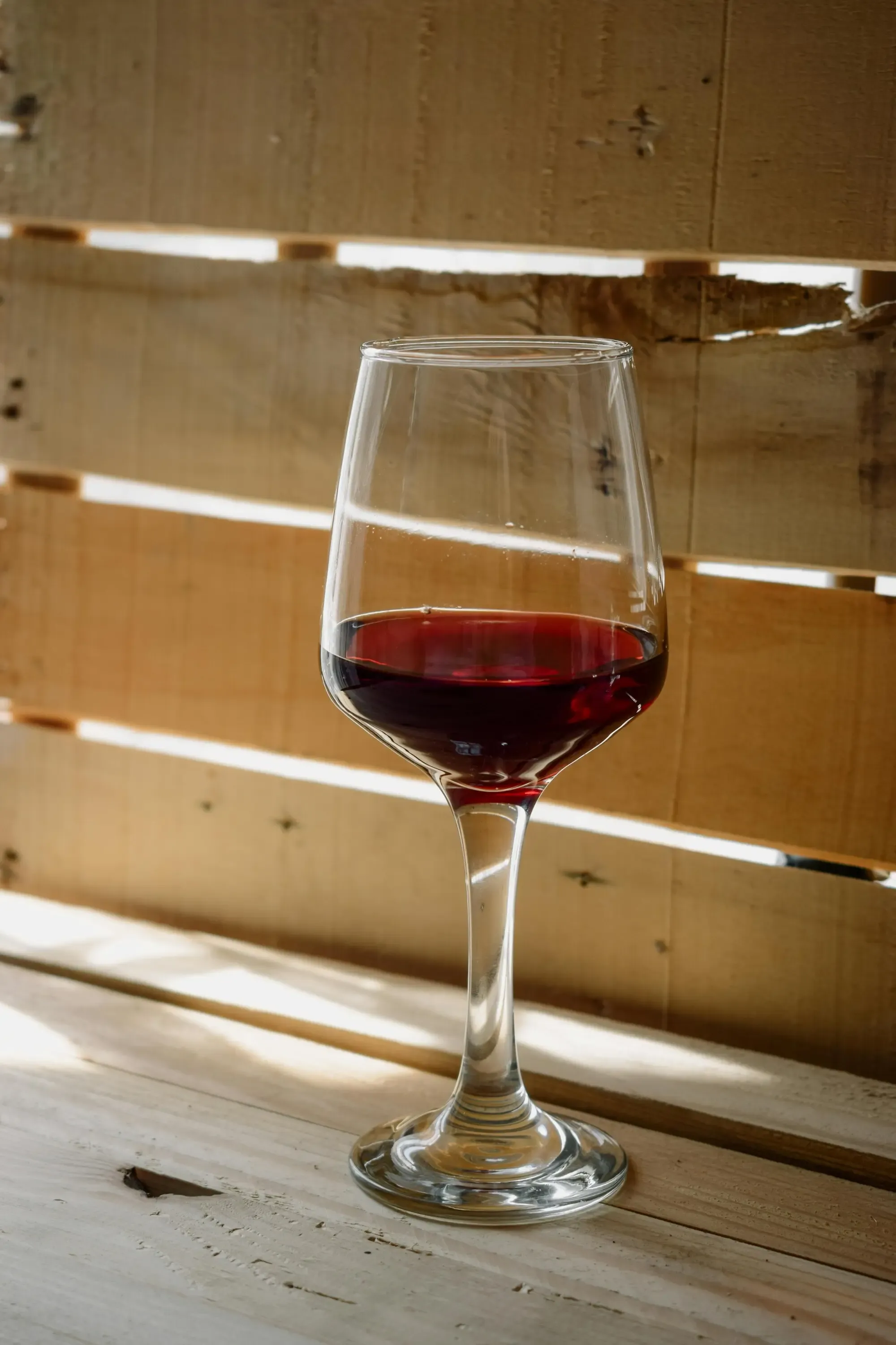 Glass of red wine on a rustic wooden table.